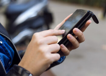Jovem mulher usando seu celular na rua.